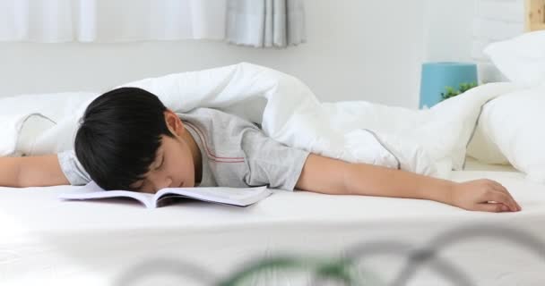 Asiatiska söt pojke en bok innan sista testet hemma. vara en sömn efter Läs — Stockvideo