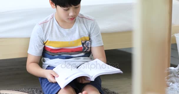 读一本书前最后测试在家里的亚洲可爱男孩 . — 图库视频影像