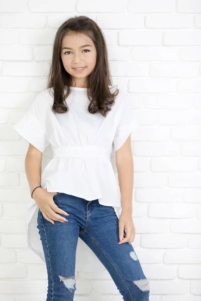 Menina bonito feliz com jeans azuis e sorrindo olhando para a câmera . — Fotografia de Stock