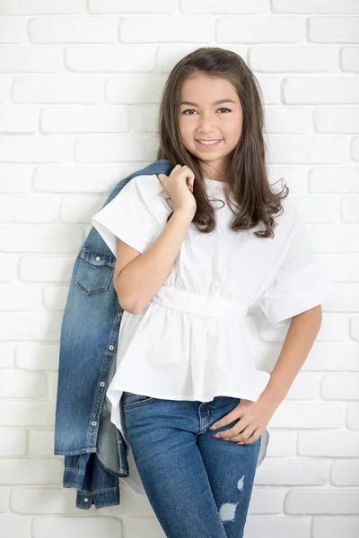 Menina bonito feliz com jeans azuis e sorrindo olhando para a câmera . — Fotografia de Stock