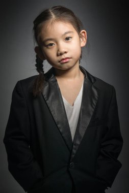 Siyah takım elbise ve kameraya bakarak mutlu sevimli kız portresi.