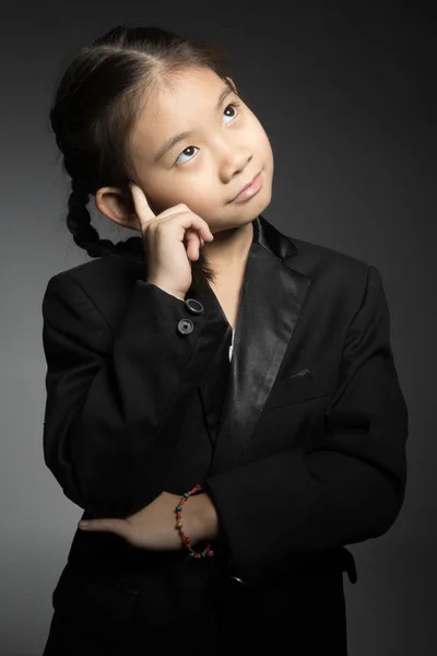 Retrato de menina bonito feliz em terno preto está pensando . — Fotografia de Stock