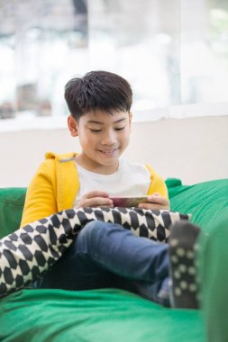 Mutlu Asyalı çocuk gülümsemek yüz ile cep telefonu kullanarak .