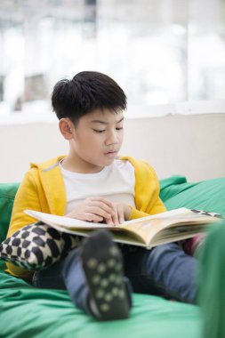 Mutlu Asyalı çocuk gülümsemek yüz kitap okuma.