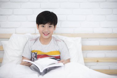 Asyalı çocuk dinlenme yatak ve okuma kitabı