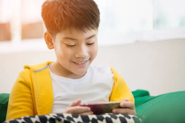 Feliz asiático chico usando celular con sonrisa cara  . — Foto de Stock