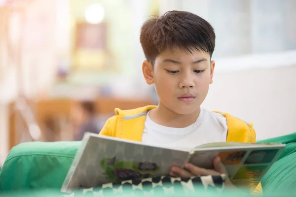 Feliz asiático niño leyendo libro con sonrisa cara . —  Fotos de Stock