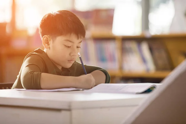 Feliz asiático niño haciendo tarea con sonrisa cara . — Foto de Stock