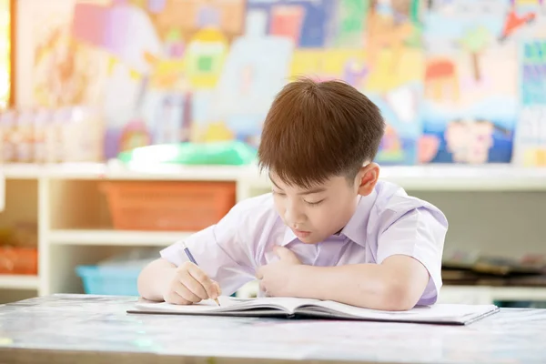 Portrait of happy asian cute child doing homework with smile fac — Stock Photo, Image