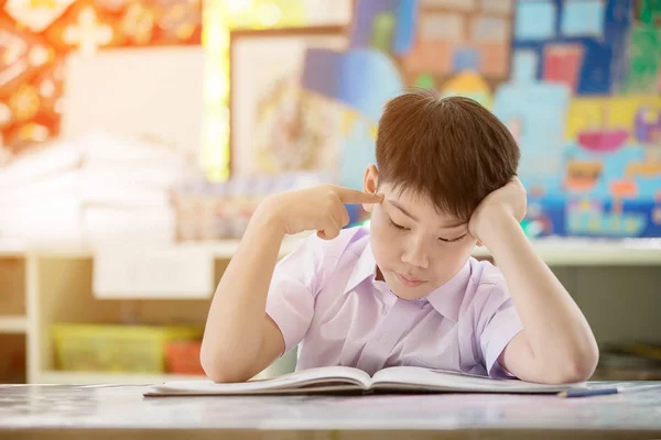 Feliz asiático niño leyendo libro y pensar en que — Foto de Stock