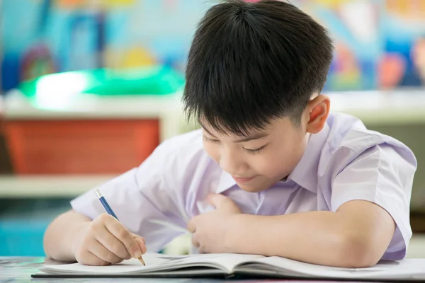 Cabeça tiro retrato de feliz asiático bonito criança fazendo lição de casa com — Fotografia de Stock