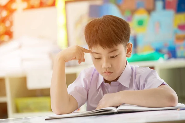 Gelukkig Aziatische kind lezen boek met glimlach gezicht op school . — Stockfoto