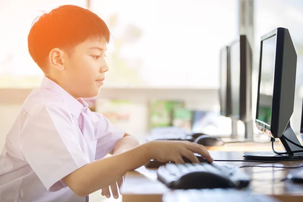 Feliz asiático chico en estudiante uniforme usando computadora en escuela  . —  Fotos de Stock