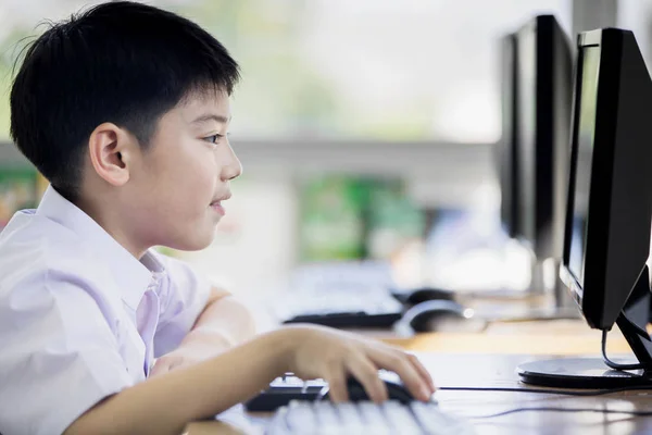 Gelukkig Aziatisch in uniform van de student met behulp van computer op school . — Stockfoto