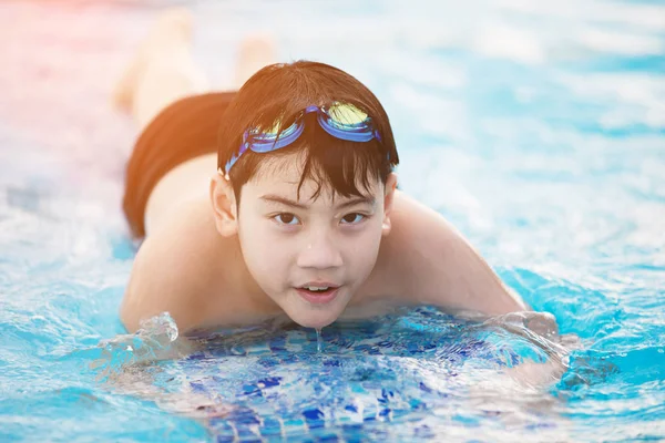 Щасливий азіатський хлопчик у купальнику піднімається в басейн — стокове фото
