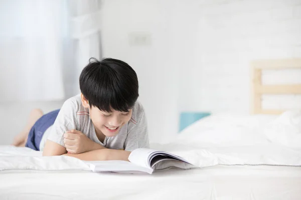Ασίας αγόρι ανάπαυση στο κρεβάτι και την ανάγνωση βιβλίο — Φωτογραφία Αρχείου