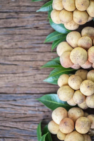 Langat thailändische Früchte mit grünem Laub auf hölzernem Hintergrund, — Stockfoto