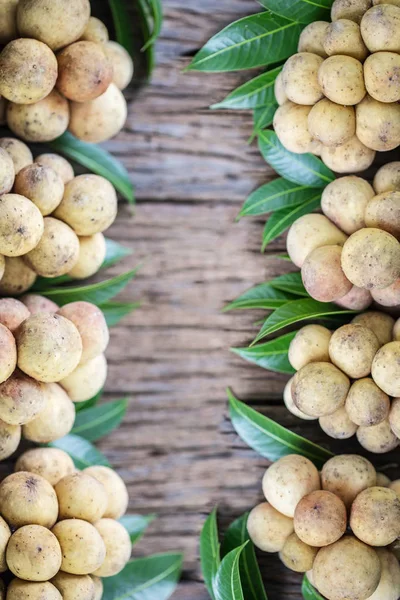 LangSat Thai frutta con foglie verdi su sfondo di legno , — Foto Stock