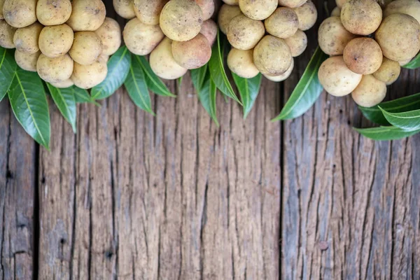 Buah LangSat Thai dengan daun hijau dengan latar belakang kayu , — Stok Foto