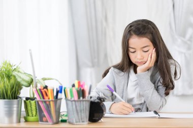 Sevimli Asya kız bir şey ile renkli kalemler kağıt yazma