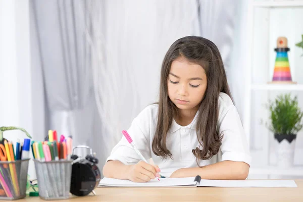 Carino Asia ragazza scrivere qualcosa in carta con matite di colore — Foto Stock