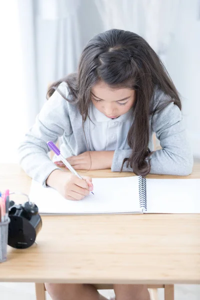 Χαριτωμένο κορίτσι της Ασίας κάτι γραπτώς σε χαρτί με μολύβια χρώματος — Φωτογραφία Αρχείου
