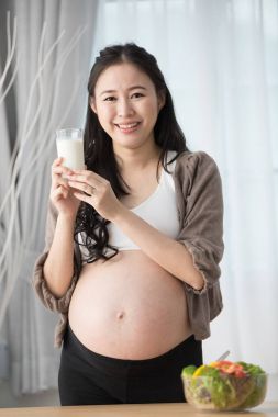 Asyalı hamile kadın üzerinde sağlıklı sebze ve süt ile mutfak.