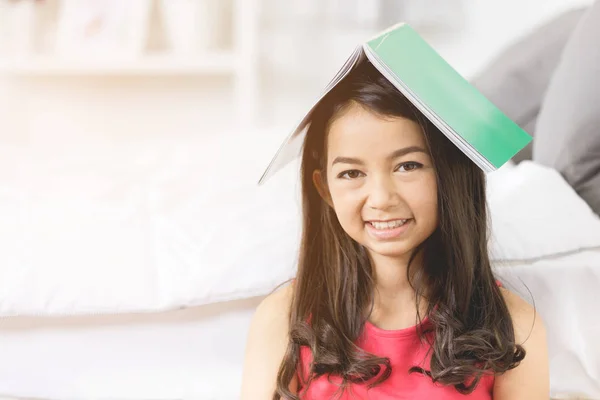 Heureuse fille asiatique avec livre vert sur sa tête , — Photo