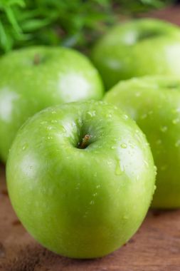 Su dropletson ahşap arka plan ile olgun yeşil elma