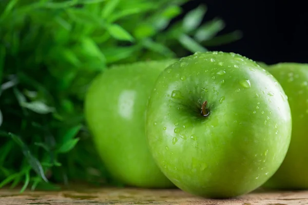 Dojrzałe jabłka zielone wody dropletson drewniane tła — Zdjęcie stockowe