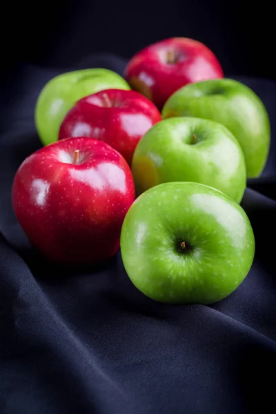 Vert et rouge de pommes sur fond de tissu noir — Photo