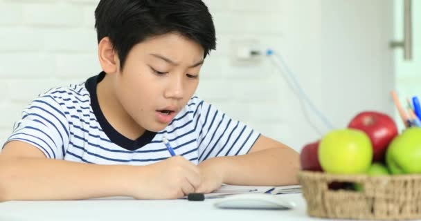 Lindo asiático chico haciendo tarea en casa con sonrisa cara . — Vídeos de Stock