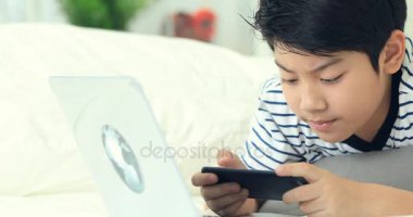 Smartphone ve daktilo ile gülümsemek yüz holding sevimli Asya çocuk eller.