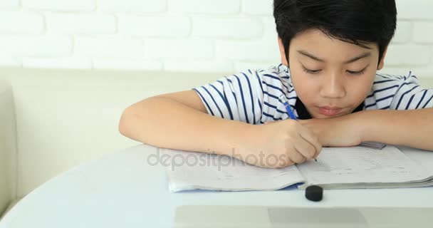 可爱的亚洲男孩在家里做作业与微笑的脸. — 图库视频影像