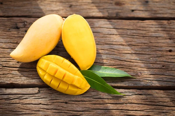 Dojrzałe mango w plasterkach na zalesionych deska z zielonych liści. — Zdjęcie stockowe