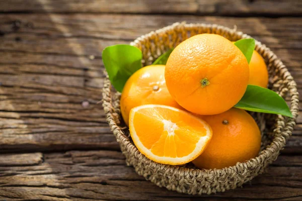 Свежие оранжевые фрукты в корзине на деревянном столе . — стоковое фото