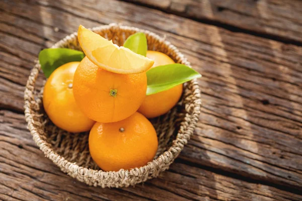 Fresh orange fruits in basket on wood table. — Stock Photo, Image
