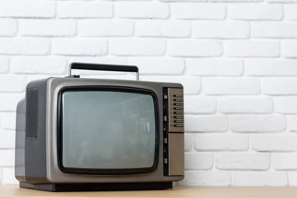 Oude TV op een witte bakstenen muur achtergrond. — Stockfoto