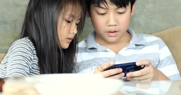 幸せなアジア家族の妹や弟のベッドの上の携帯電話. — ストック動画
