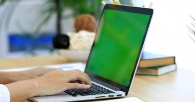 Asyalı kadın el ile yeşil ekran dizüstü bilgisayarda yazarak.