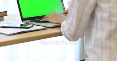Asyalı kadın el ile yeşil ekran dizüstü bilgisayarda yazarak.