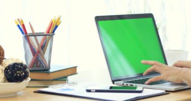 Asyalı kadın el ile yeşil ekran dizüstü bilgisayarda yazarak.