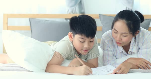 Glückliche asiatische Bruder und Schwester ruhen auf dem Bett und schreiben mit Lächeln Gesicht . — Stockvideo