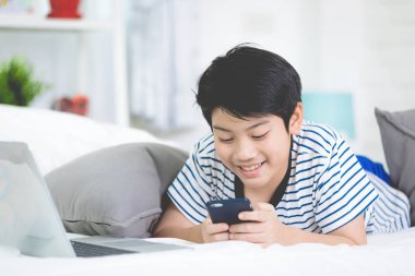 Sevimli Asya çocuk dinlenme yatak ve akıllı cep telefonu kullanma .