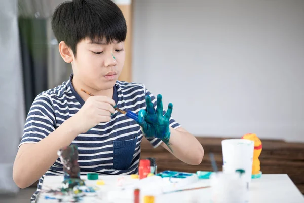 Щасливий азіатський хлопчик малює фарбу . — стокове фото
