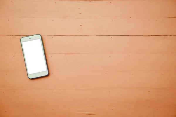 Telefon komórkowy z biały ekran makieta na tle stół z drewna — Zdjęcie stockowe