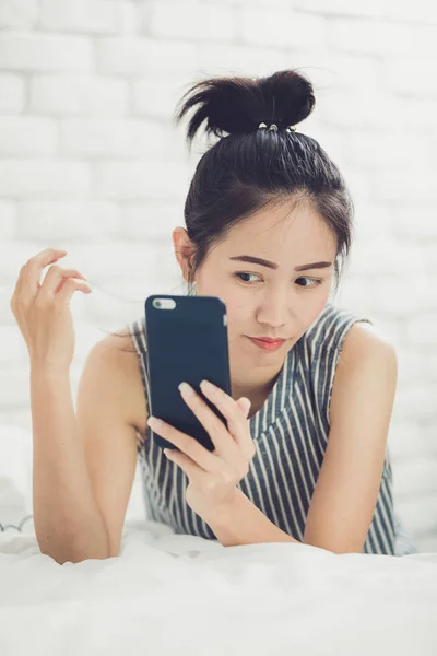 Happy asian girl reading smart phone with smile face on bed . — Stock Photo, Image