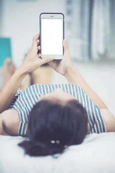 Asian woman rest on bed  .Hand holding smart phone . — Stock Photo, Image