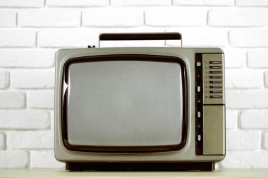 Beyaz tuğla duvar arka plan üzerinde eski televizyon.