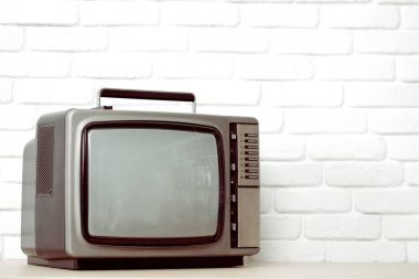 Beyaz tuğla duvar arka plan üzerinde eski televizyon.